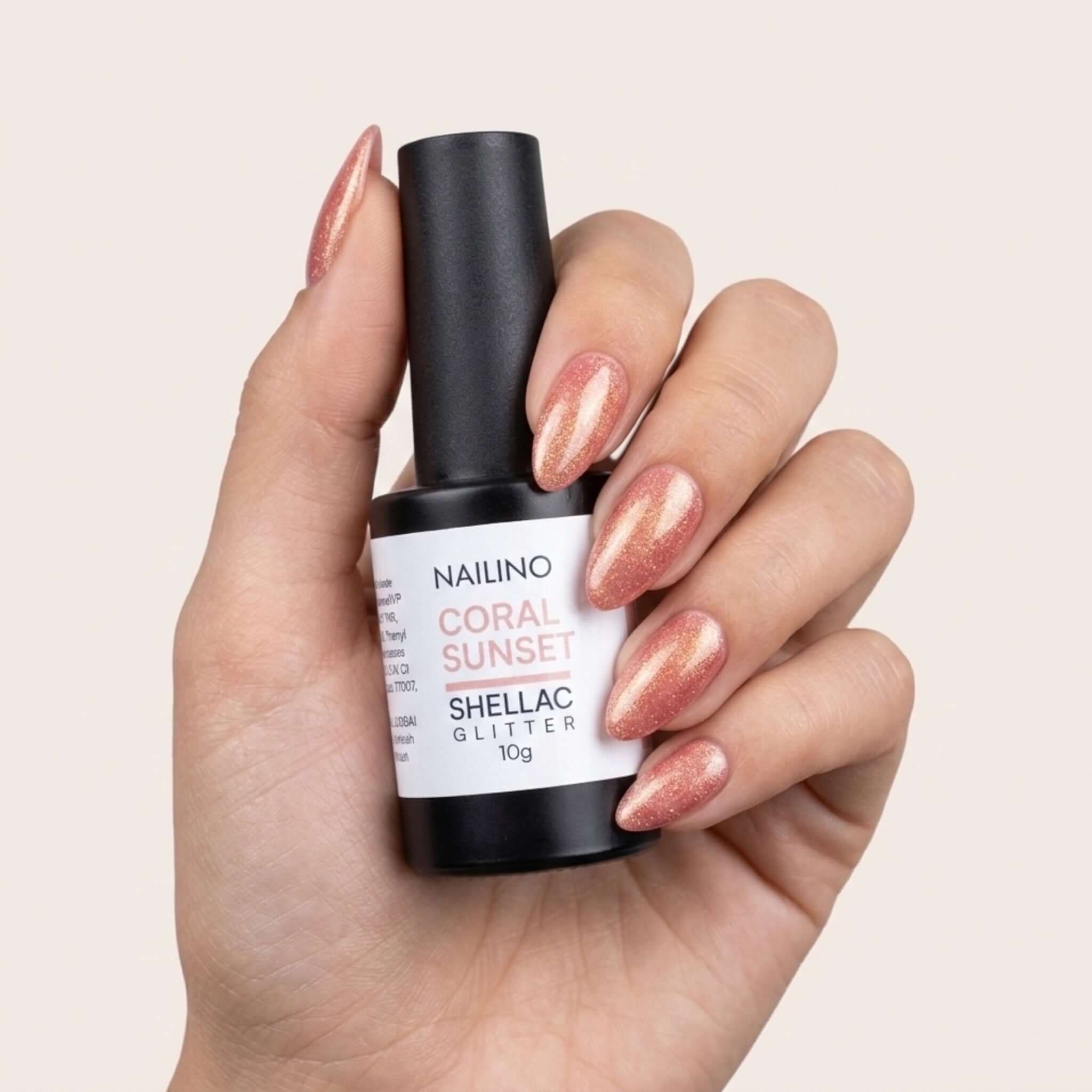 NAILINO Shellac Coral Sunset - Koralle Gold Glitzer Nagellack in einer Hand mit strahlenden Nägeln