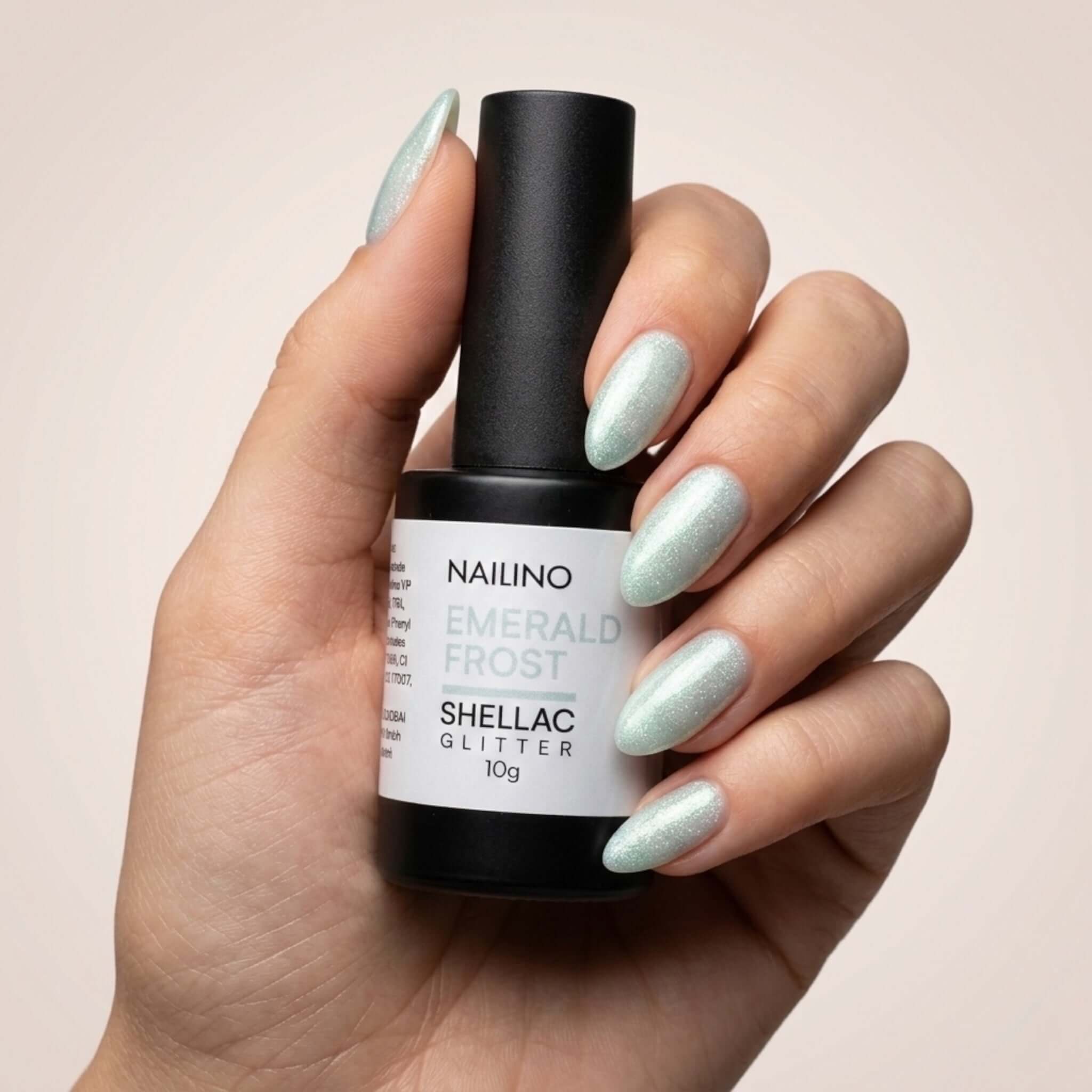 NAILINO Shellac Emerald Frost – Flasche mit kühlem Smaragd-Glanz und Silber-Glitter in der Hand.