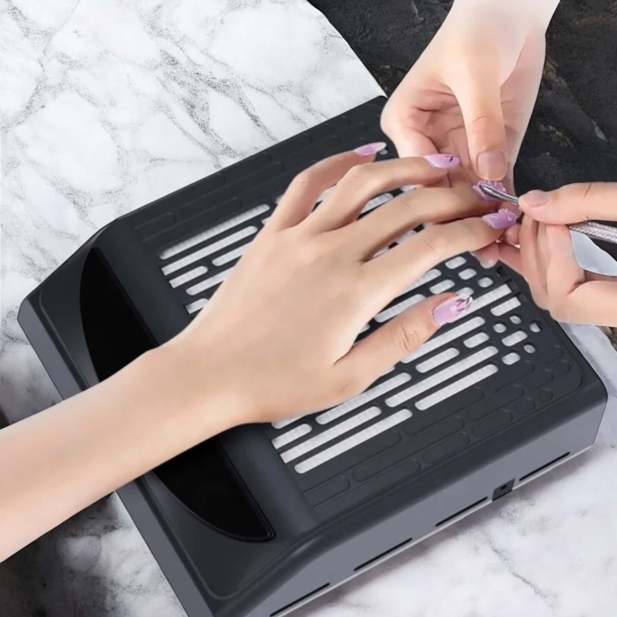 Schwarzer Nagelstaub-Absauger mit integrierter Armauflage während Maniküre im Einsatz