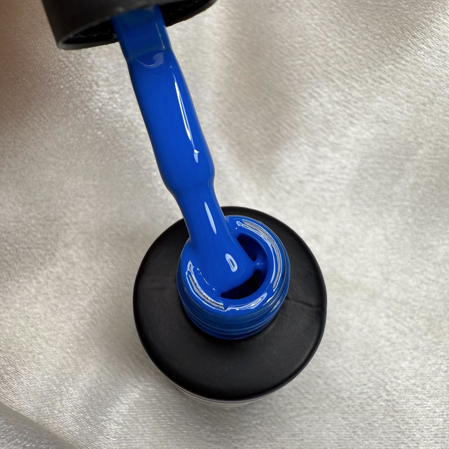 NAILINO Shellac Royal Azure bottle with bright royal blue nail polish pouring out.