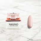 NAILINO Farbgel Soft Blush Nagellack und nagelgeklebte Oberfläche auf Marmorhintergrund.