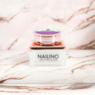 NAILINO Farbgel Plum Passion intensives Pflaumenlila Nagelgel in einem schicken Behälter auf einem Marmortisch