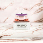 NAILINO Farbgel Royal Orchid in luxuriöser Verpackung vor rosa Marmorhintergrund